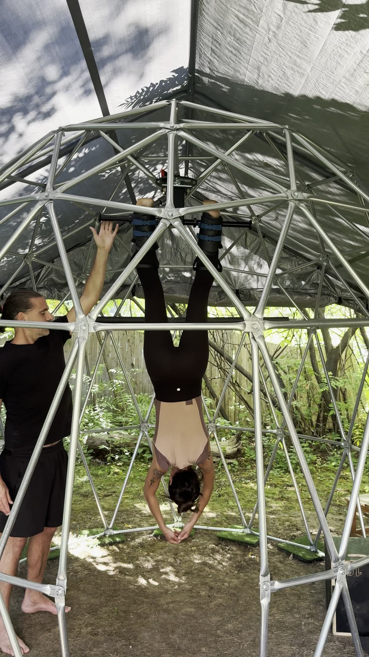 Matthew guiding a guest suspended upside down in the Unwind Machine, inside the open dome.